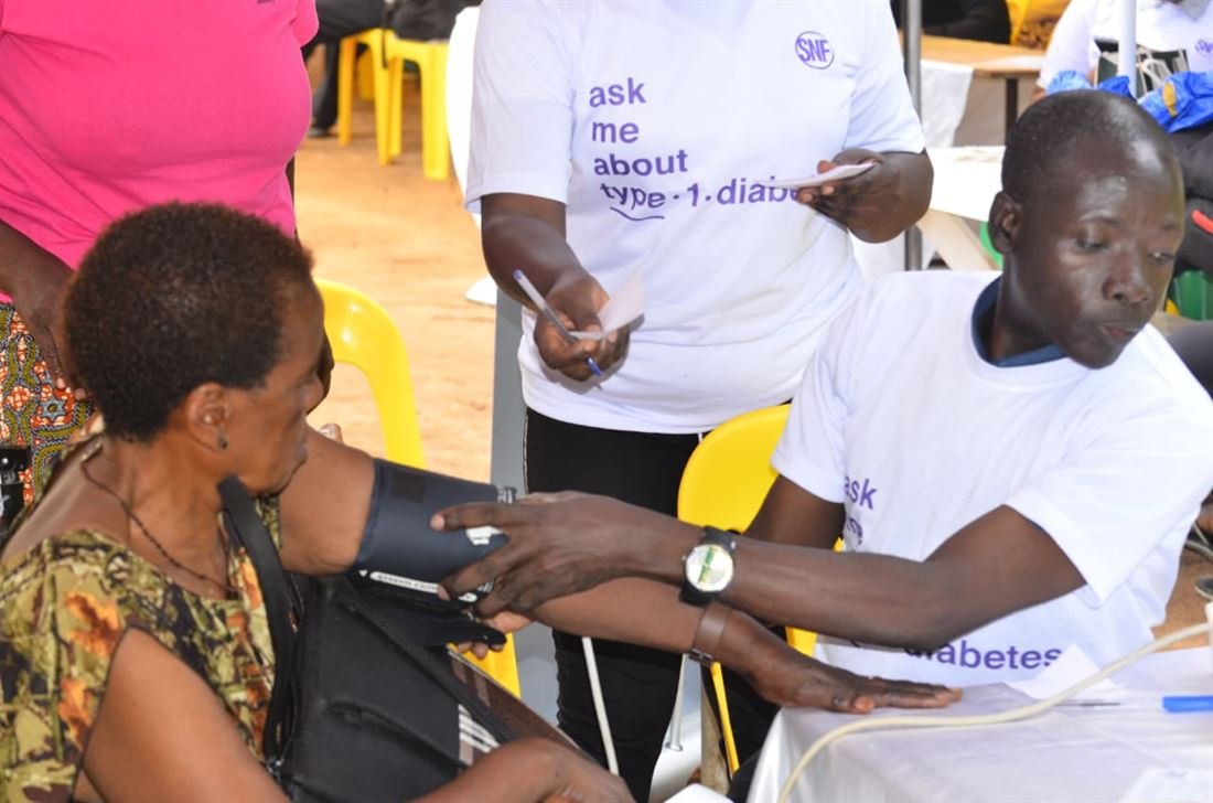 A health worker takes a woman's blood pressure reading during a community screening session.