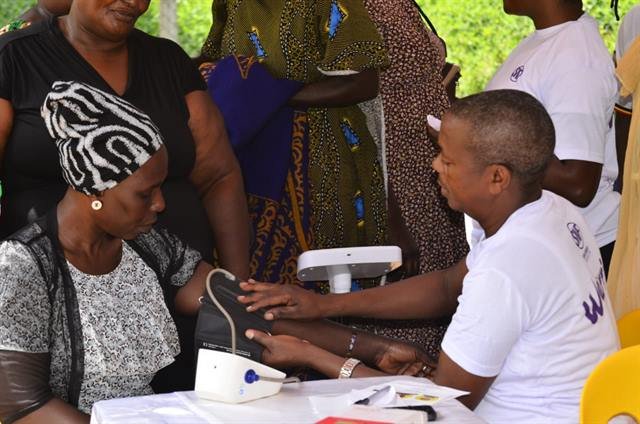 A health worker fits a blood pressure cuff to a woman’s arm at a screening outreach.