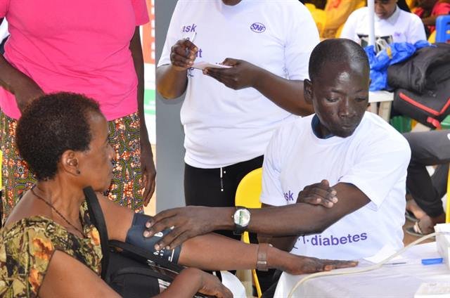 A health worker measures a woman’s blood pressure at a community diabetes event.