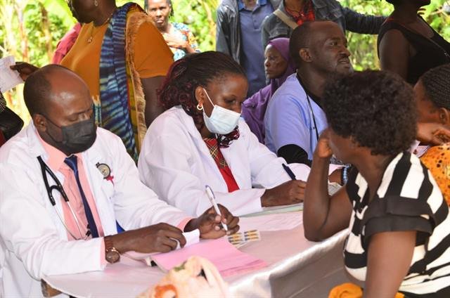 Two clinicians in white coats consult with a community member at an RDAF outreach.
