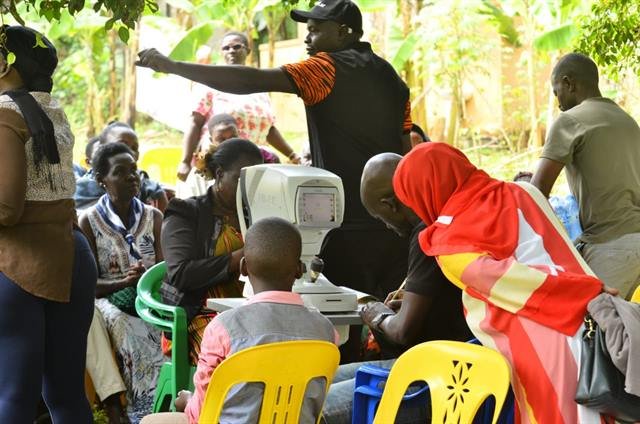 A community member is screened using diagnostic equipment while others look on.