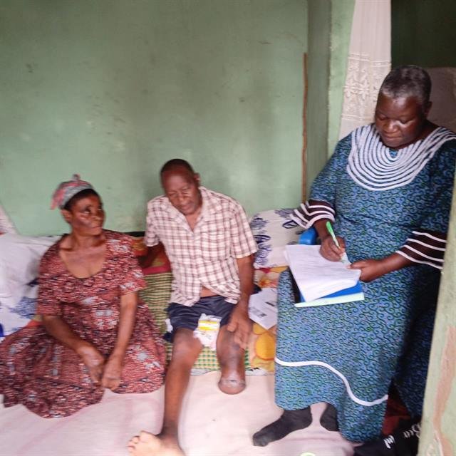 An RDAF team member writes notes during a home visit while family members sit together.