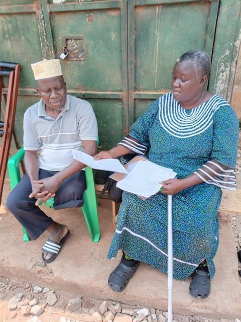 Two community members using mobility aids sit together reading RDAF paperwork.